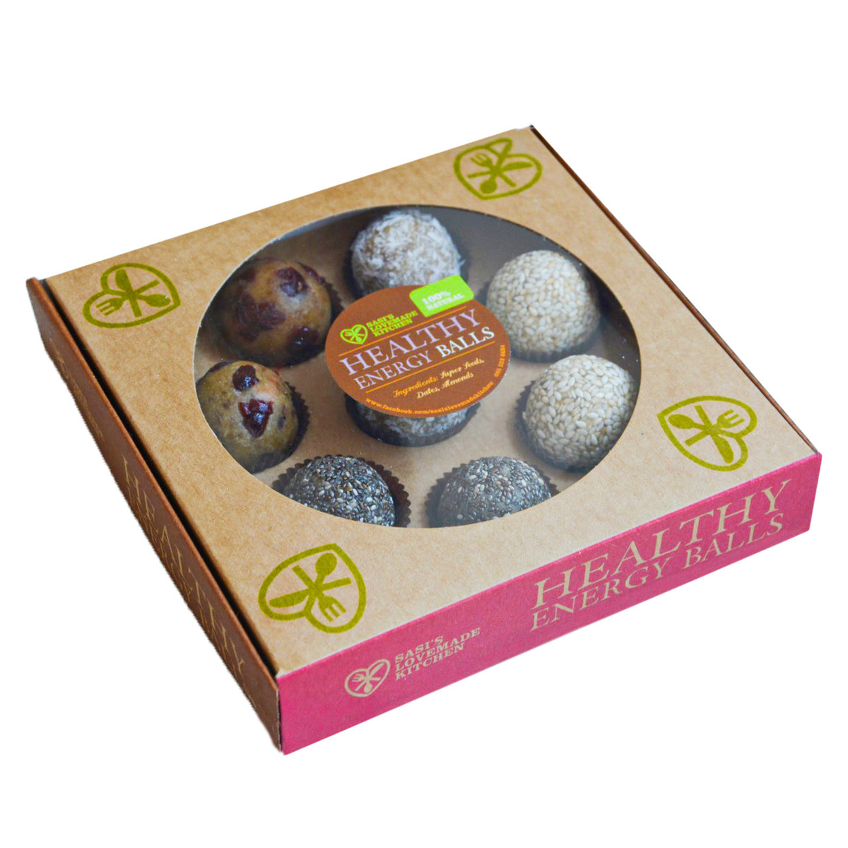 A box of Sasi's Lovemade Kitchen energy balls in a brown kraft paper package with a pink side panel and a clear circular window showing the round balls inside. The package has green leaf and fork icons and a round orange label reading 'Healthy Energy Balls'.