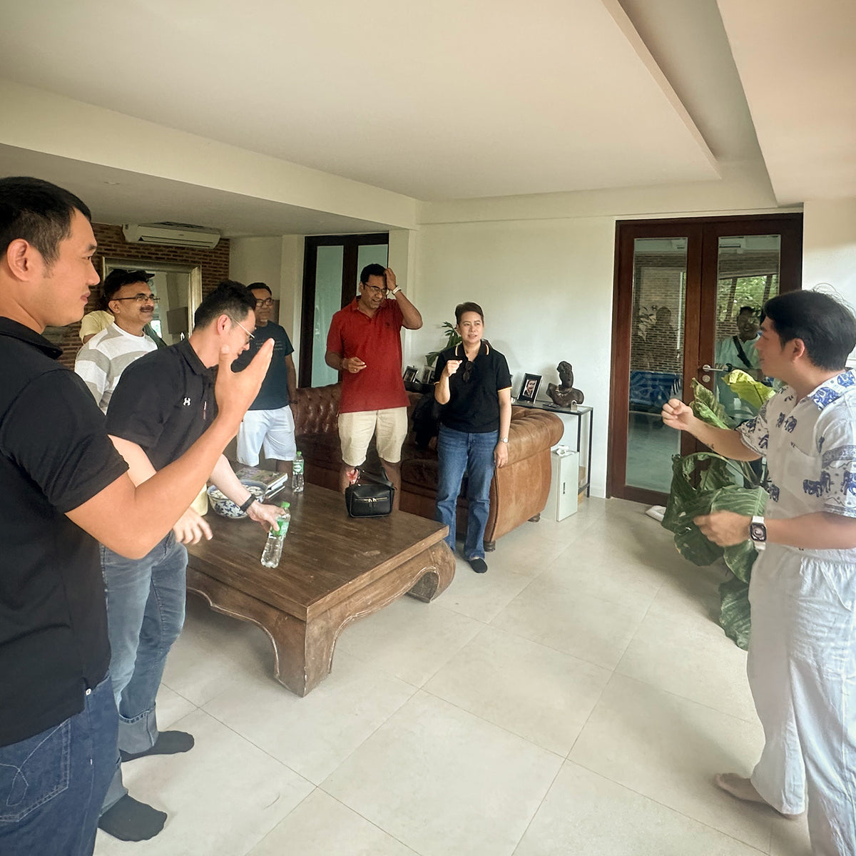 A team-building corporate event with a group of people standing in a modern living room, one man holding  motivational speech.