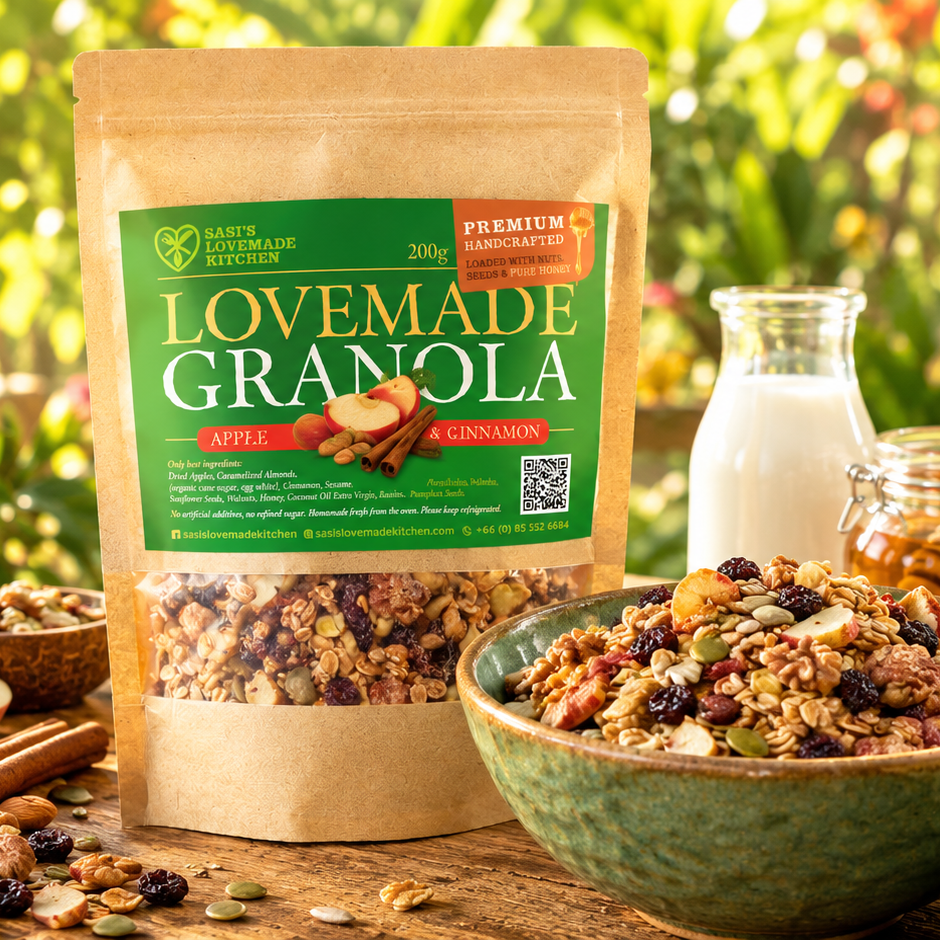 A s200 gtand-up pouch of Sasi's Lovemade Kitchen  Granola in Apple & Cinnamon flavor, displayed next to a bowl filled with the granola and a glass bottle of milk on a rustic wooden table with a blurred outdoor garden background.